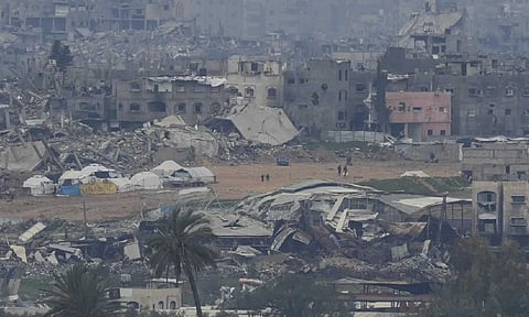 Palestinians are seen near destroyed buildings by Israeli bombardments inside the northern Gaza Strip as seen from southern Israel (AP)