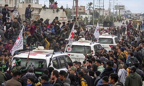 Palestinians gather as Hamas fighters escort Red Cross vehicles carrying Israeli captives who have been held hostage by Hamas in Gaza (AP)