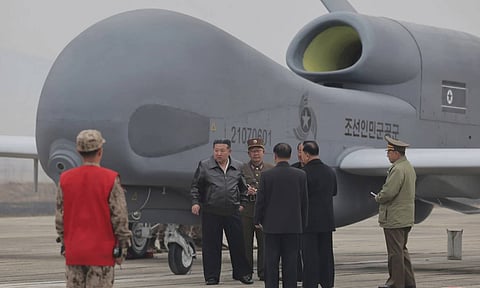 The North Korean government, its leader Kim Jong Un, center left in a black jacket, stands by what appeared to be a large reconnaissance drone at an undisclosed location in North Korea (AP)