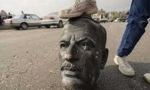 An opposition fighter steps on a broken bust of the late Syrian President Hafez Assad in Damascus