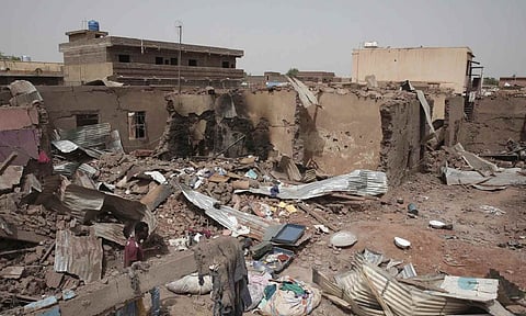 A man walks by a house hit in recent fighting in Khartoum, Sudan, an area torn by fighting between the military and the notorious paramilitary Rapid Support Forces, on April 25, 2023 (AP)&nbsp;&nbsp;