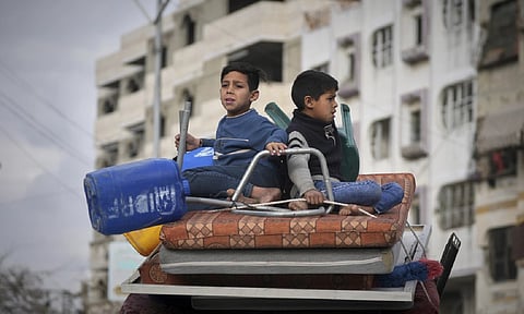 Two boys sit on a mattress as they ride on their family car while s fleeing from east to west of Gaza City after the Israeli military issued evacuation orders in the area (AP)