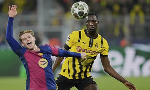 Barcelona’s Frenkie de Jong, left, duels for the ball with Dortmund’s Serhou Guirassy during the Champions League quarterfinals (AP)