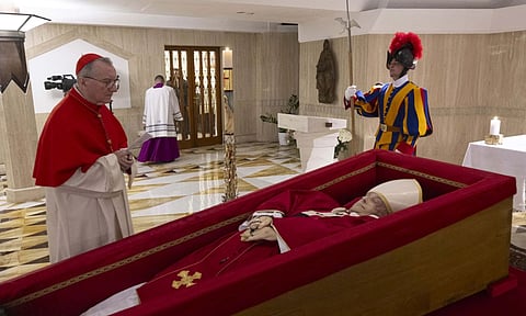 Vatican Secretary of State Cardinal Pietro Parolin, left, prayers in front of the body of Pope Francis laid out in state inside his private chapel at the Vatican (AP)
