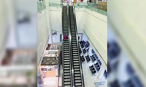 A passenger walking down the steps of a static escalator