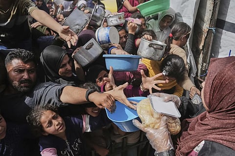 Palestinians clamber to receive donated food at a distribution center in Beit Lahiya in the northern Gaza Strip (AP)