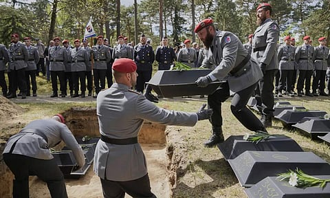 German soldiers carry the small coffins with the remains of fallen German soldiers of WWII to the grave during a funeral service at a memorial site for fallen soldiers in Halbe, Germany (AP)