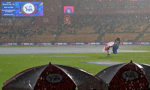 A ground official covers the spidercam as it rains before an Indian Premier League (IPL) 2025 T20 cricket match between Royal Challengers Bengaluru and Kolkata Knight Riders, at the M Chinnaswamy Stadium, in Bengaluru, Karnataka, Saturday, May 17, 2025 (PTI)