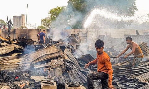 People look through charred debris after a fire broke out at a slum area at Sector 52, in Gurugram, Saturday, May 17, 2025 (PTI)