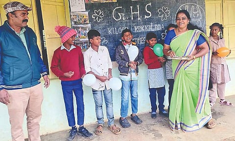 A teacher welcomes students at the school in the Nilgiris