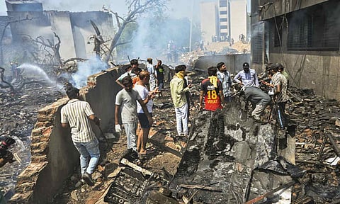 People stand near the debris of the Air India plane that crashed moments after taking off from the airport, in Ahmedabad, Thursday, June 12, 2025 (PTI)&nbsp;