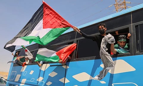 1,500 people wave Palestinian flags from a bus as the group travels towards Gaza (AP)