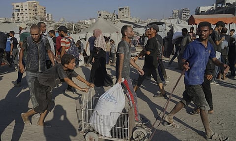 Palestinians carry sacks of flour unloaded from a humanitarian aid convoy that reached Gaza City from the northern Gaza Strip (AP)