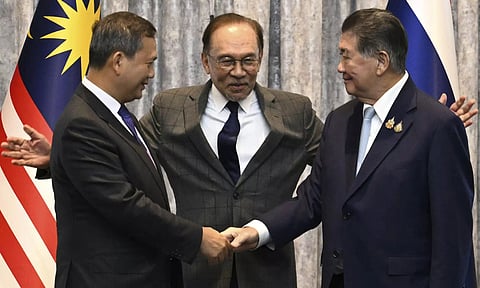 Cambodia's Prime Minister Hun Manet, left and Thailand's acting Prime Minister Phumtham Wechayachai, right shake hands as Malaysia's Prime Minister Anwar Ibrahim gestures after talks on a possible ceasefire between Thailand and Cambodia (AP)