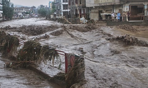 Local residents look at flash flooding due to heavy rains in a neighborhood of Mingora, the main town of Swat Valley, northwestern Pakistan (AP)