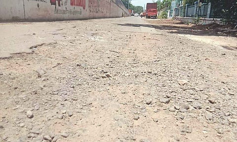 Potholes over the uneven surface of the at-grade service road filled with gavel, mud and stones