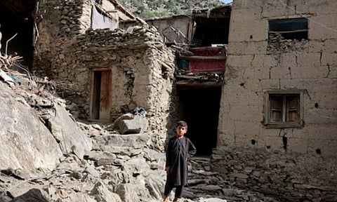 A boy stands in front of houses damaged by a deadly earthquake that struck Afghanistan's Kunar and Nangarhar provinces at Masud village in Nurgal district, Afghanistan (Reuters)