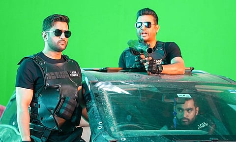 Dhoni and Madhavan standing on top of a car wearing task force attire with a lot of others accompanying them. (IANS)