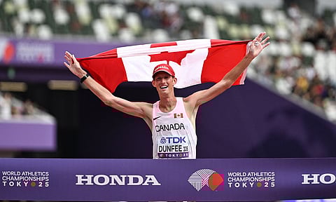 Canada’s Evan Dunfee holds a Canadian flag crossing the finish line as he wins gold at the men’s 35km race walking event