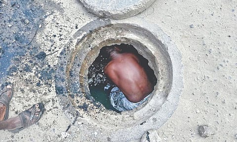 A representative image of a worker cleaning a sewage drain
