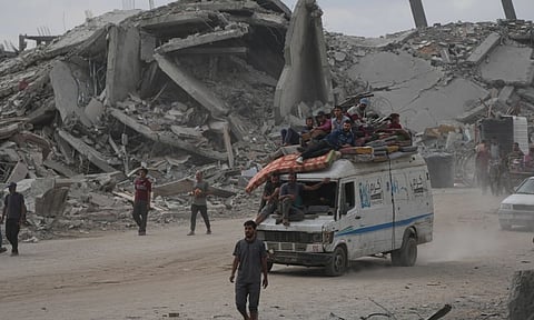 Displaced Palestinians ride on a van loaded with their belongings amid rubble in Gaza City, Sunday, Oct. 12, 2025, after Israel and Hamas agreed to a pause in their war and the release of the remaining hostages. (Photo: AP)