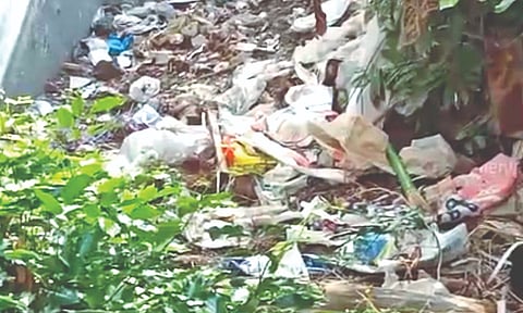 Discarded furniture, tree debris, and plastic waste piled up on the plot located along Munu Adhi Street