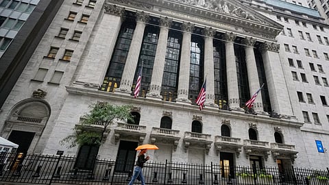A woman with an umbrella passes the New York Stock Exchange