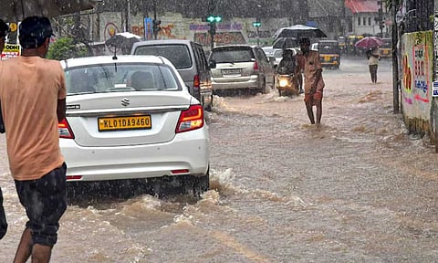 Commuters wade through a waterlogged road amid rains, in Thiruvananthapuram (PTI)