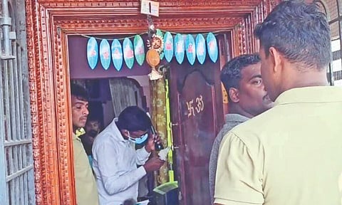 Police and fingerprint bureau personnel inspect the crime scene