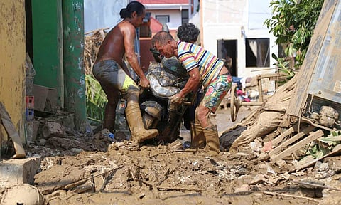 Residents carry a motorcycle along a muddied street caused by Typhoon Kalmaegi, in Liloan, Cebu province, central Philippines on Thursday, Nov 6, 2025 (AP)