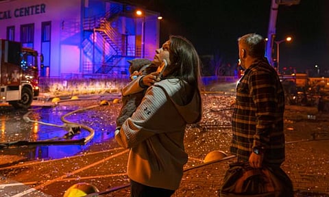 People watch as emergency services personnel work to extinguish a fire following a Russian attack in Kyiv, Ukraine (AP)