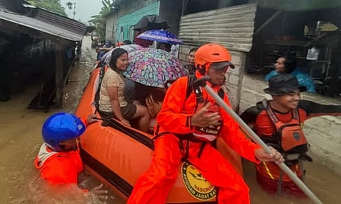 In this photo released by the Indonesian National Search and Rescue Agency (BASARNAS), rescuers on a rubber boat evacuate residents from their flooded home in North Sumatra province, Indonesia (AP)