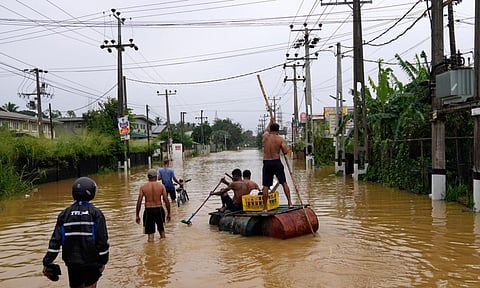 People use a crude raft to navigate a flooded street in Colombo, Sri Lanka (AP)