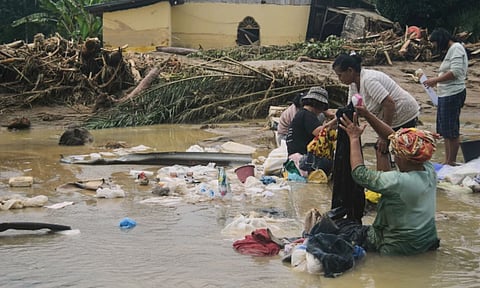 People use flood water to remove mud from clothings at a village hit by a flash flood in Batang Toru, North Sumatra, Indonesia. (Photo: AP)