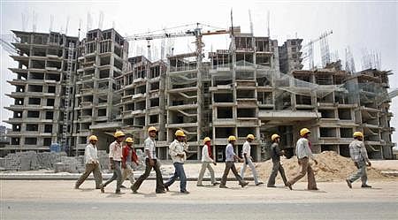 Workers walk in front of the construction site of a commercial complex