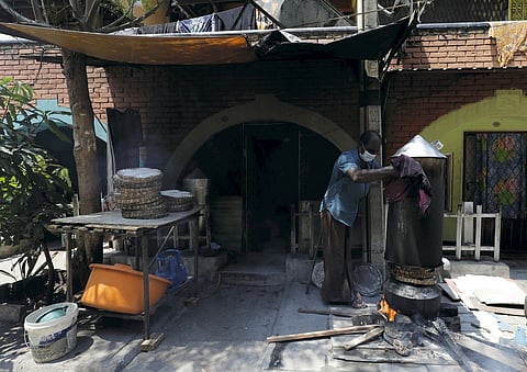 A man who runs a home based food business uses a traditional Sri Lankan wooden stove