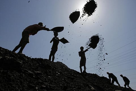 Labourers load coal on trucks