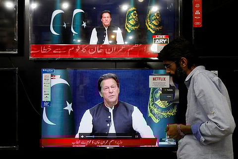 A shopkeeper tunes a television screen to watch the speech of Pakistani Prime Minister Imran Khan, at his shop in Islamabad