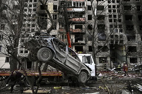 A crane removes a ruined car from in front of a destroyed apartment building after it was shelled by Russia