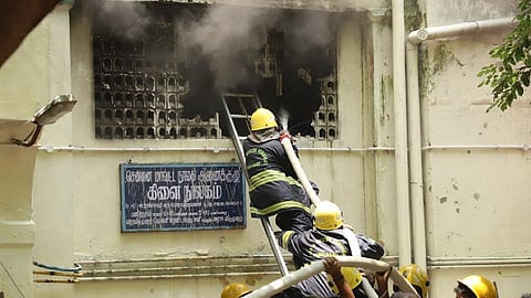 Firefighters splashing water mounting on a ladder.