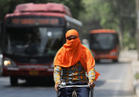 A man rides a cycle with his face fully covered, on a hot summer day