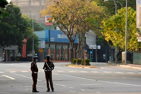 Police personnel stand guard at a checkpoint on an empty street after the authorities announced a weekend curfew in Colombo