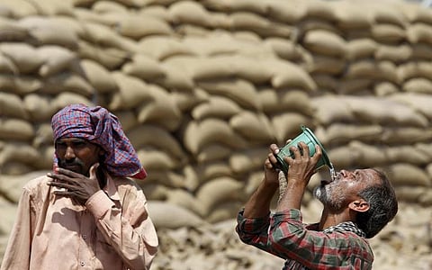A labourer drinks water as another looks on, on a hot summer day at a grain market in Chandigarh (Imge credits: Reuters)