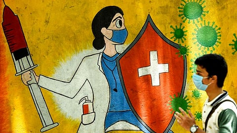 A student walks past a wall mural depicting a health worker wearing a facemask