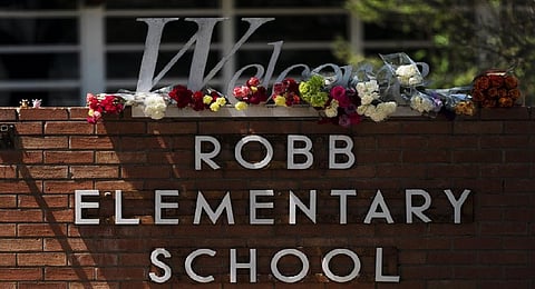 Flowers are placed around a welcome sign outside Robb Elementary School in Uvalde, Texas