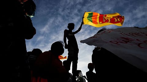 A demonstrator holding the Sri Lankan national flag is silhouetted during the protest against Sri Lankan President Gotabaya Rajapaksa