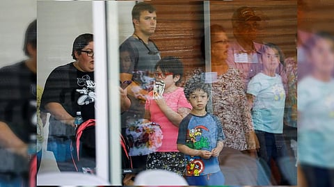 A child looks on through a glass window from inside the Ssgt Willie de Leon Civic Center, where students had been transported from Robb Elementary School after a shooting, in Uvalde, Texas