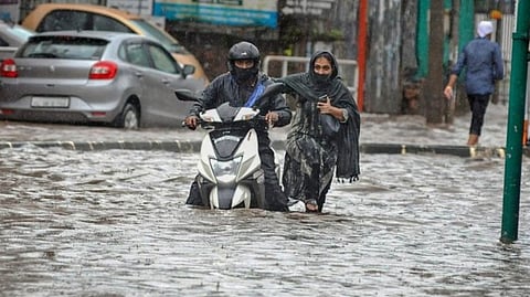 Commuters move through a waterlogged street after heavy rain