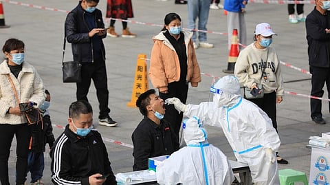 A medical worker in protective suit collects a swab from a man during a mass nucleic acid testing in Huichuan district following new cases of the coronavirus disease