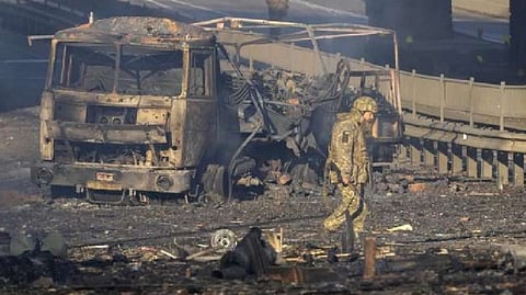 A Ukrainian soldier walks past debris of a burning military truck, on a street in Kyiv, Ukraine